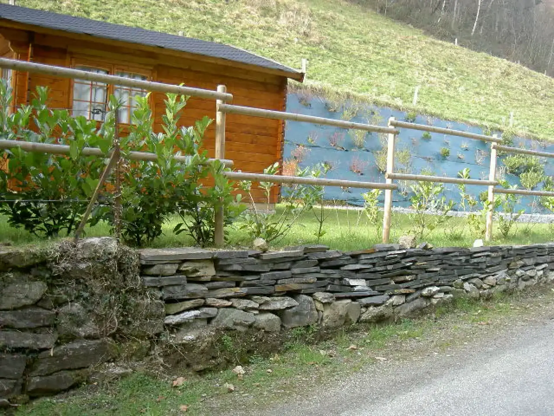 Muret en pierre et clôture en bois au bord d’un plan d’eau
