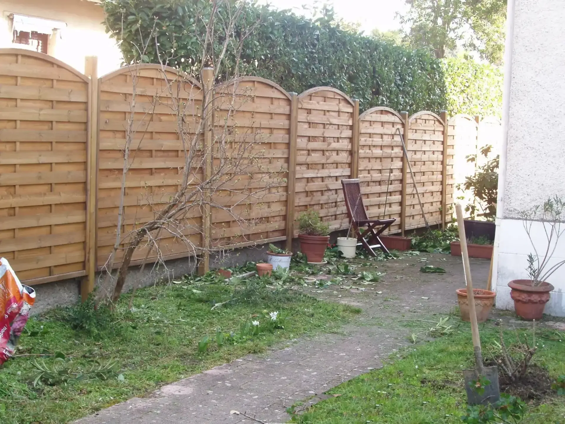 Clôture en bois à panneaux cintrés dans un jardin résidentiel.