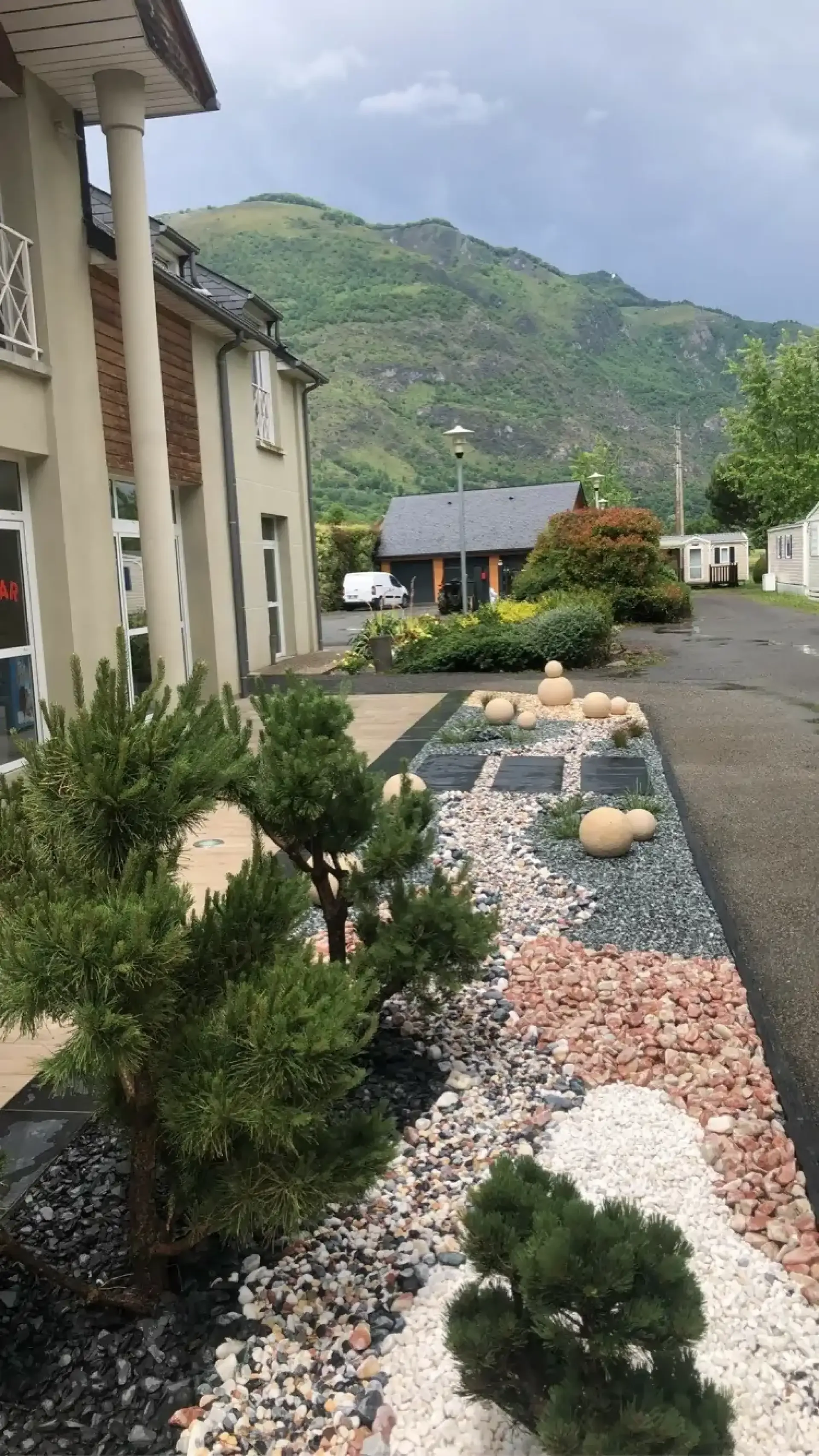 Jardin minéral composé de galets colorés, pins taillés et dalles sombres